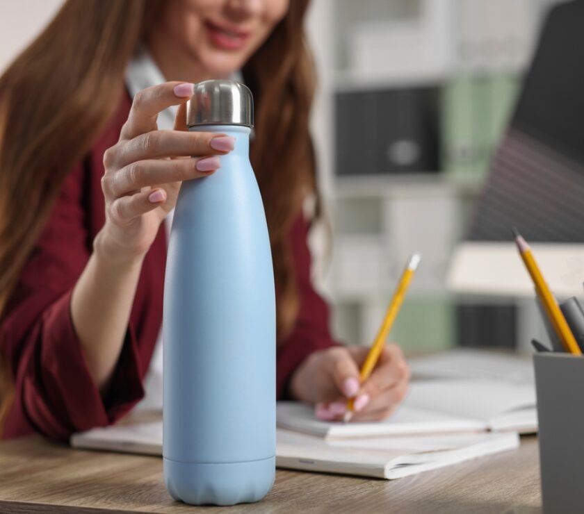 Woman,Holding,Thermos,Bottle,At,Workplace,,Closeup